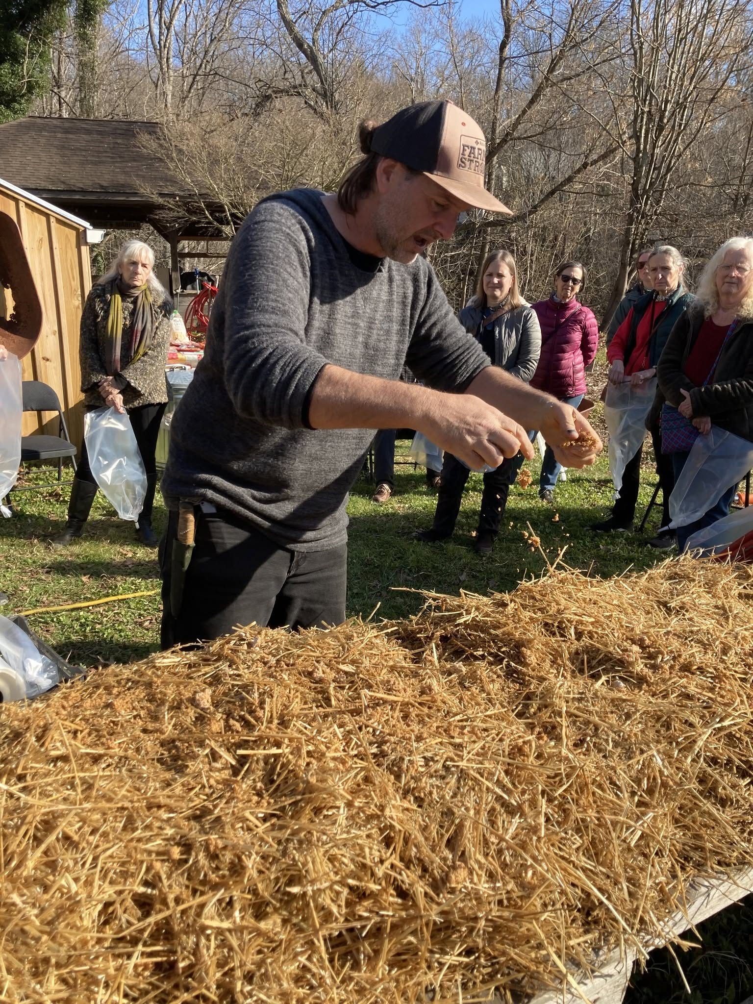 Chris Parker spreading spawn through straw while students watch